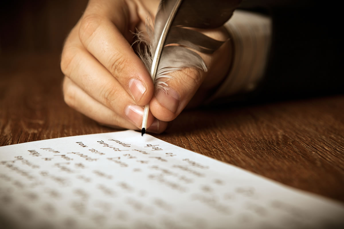 męska ręka pisząca piórem